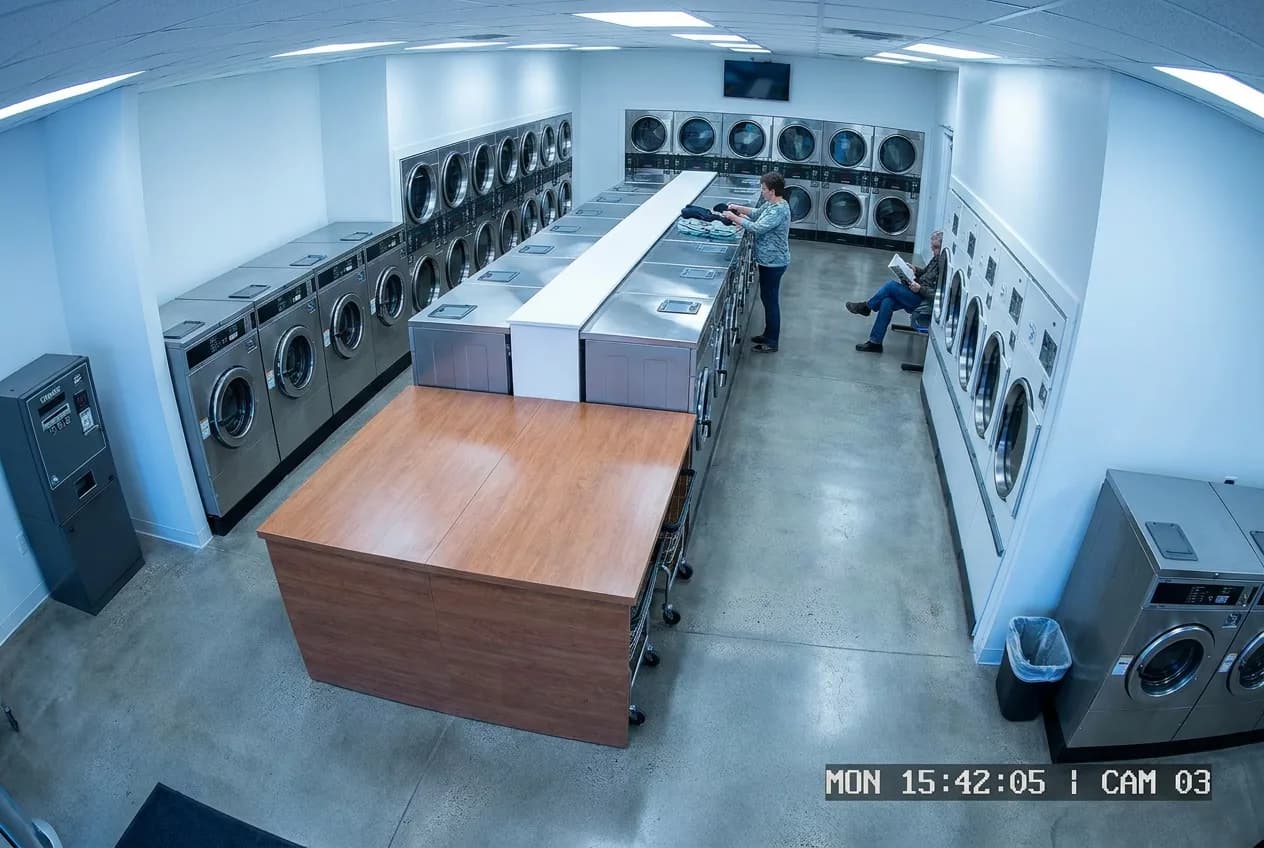 Overhead security camera view of a clean laundromat floor with rows of machines